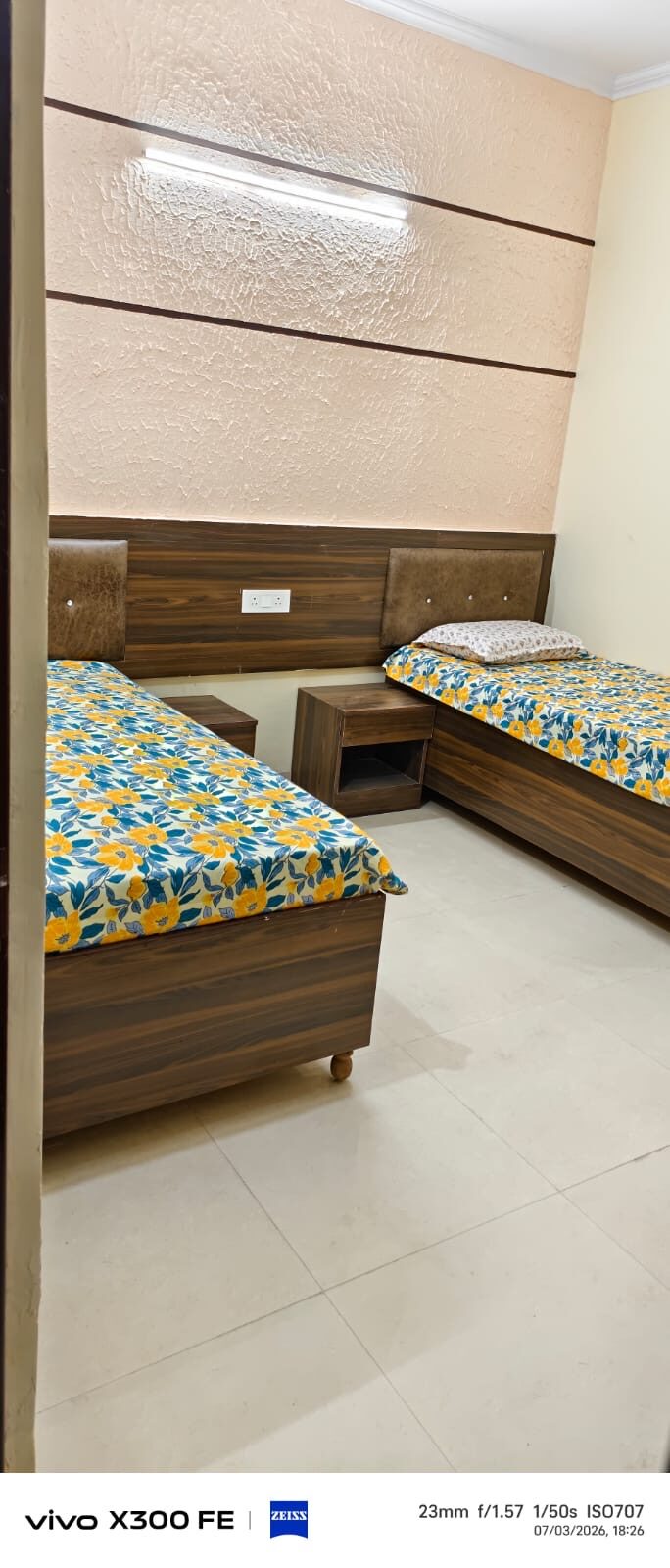 Furnished hostel room with two single beds and bedside tables
